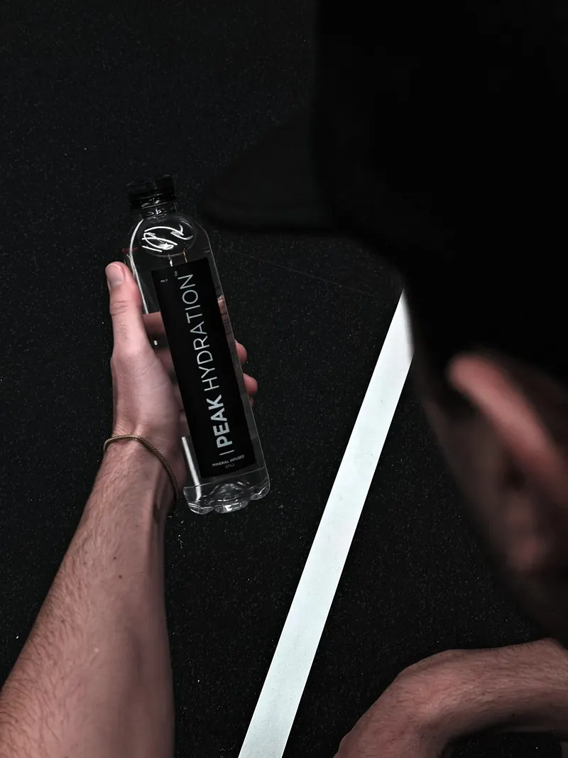 A hand holding a bottle of Peak Hydration still water