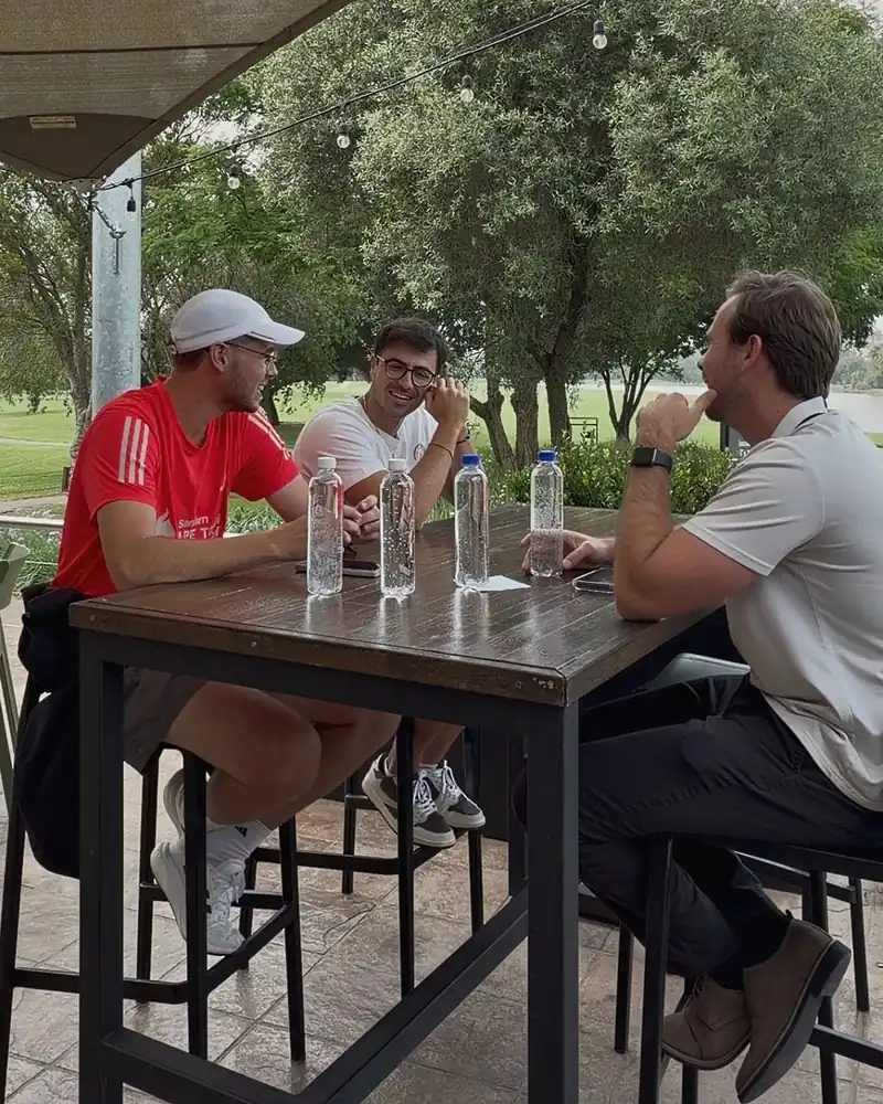 The three Peak Hydration founders talking around a table on a golf club terrace